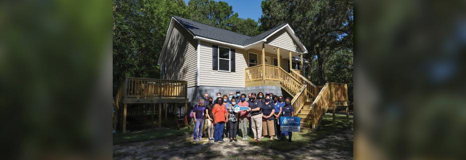 SCOR team standing in front of the last completed home from the 2015 floods